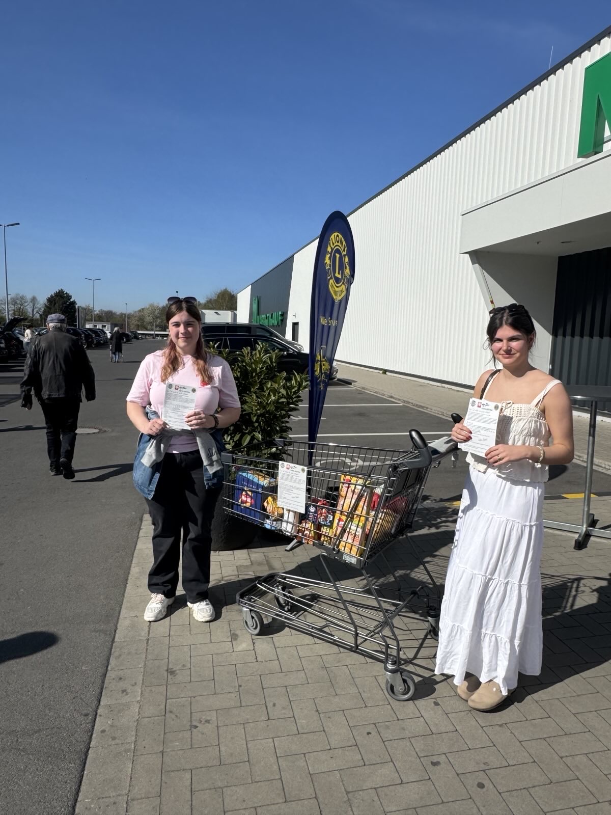 Das Bild zeigt zwei weibliche Mitglieder der LEOS vor Marktkauf in Herten Disteln für die Ein Teil Mehr Aktion im April 2025