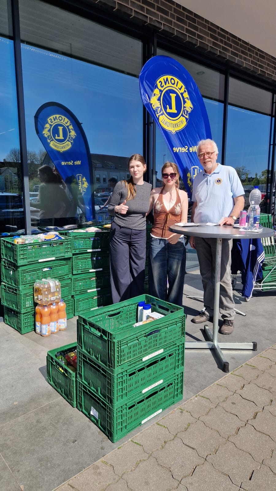 Das Bild zeigt zwei weibliche Mitglieder der LEOS und ein Mitglied der  LION vor dem Aldi Markt in Herten Disteln für die Ein teil Mehr Aktion im April 2025